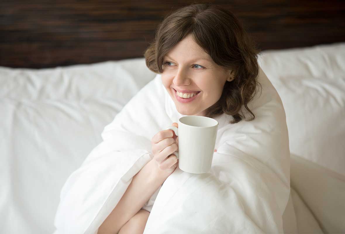 women wrapped in blanket holding a cup of coffee